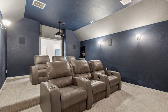 cinema with a textured wall, visible vents, light carpet, and vaulted ceiling