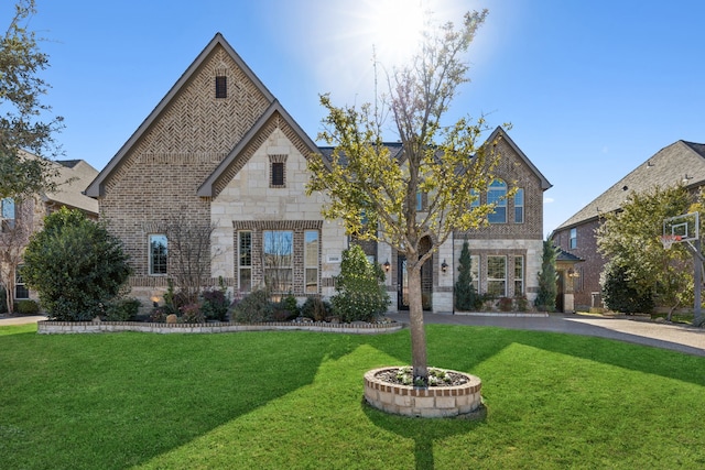 french provincial home with stone siding, brick siding, and a front yard