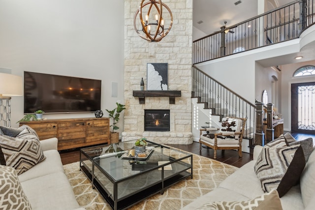 living room featuring stairway, a fireplace, a towering ceiling, and wood finished floors