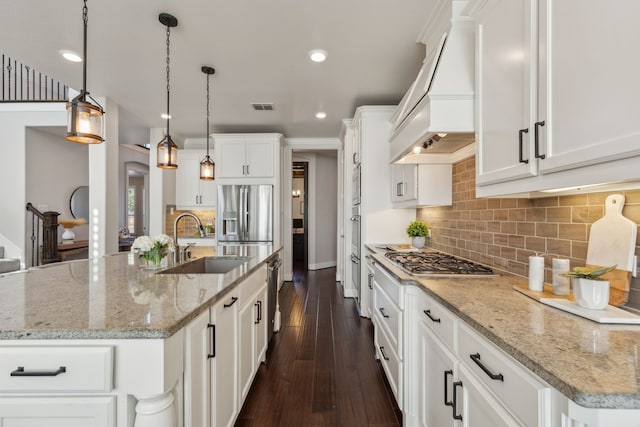 kitchen with visible vents, custom range hood, appliances with stainless steel finishes, white cabinets, and a sink