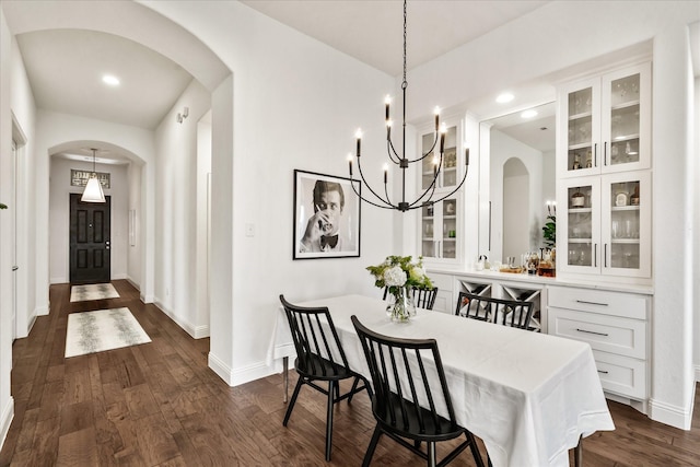 dining room featuring recessed lighting, arched walkways, baseboards, a notable chandelier, and dark wood-type flooring