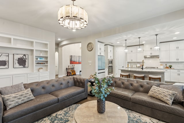 living area featuring arched walkways, wood finished floors, a notable chandelier, and recessed lighting