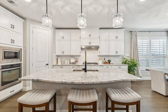 kitchen with appliances with stainless steel finishes, a breakfast bar area, a sink, and tasteful backsplash