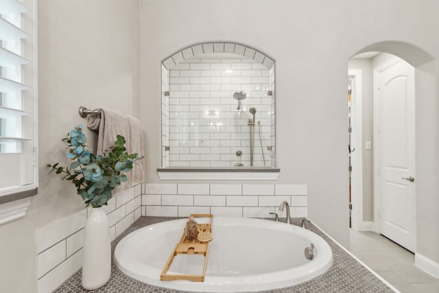 bathroom featuring a tub, tiled shower, and tile patterned floors