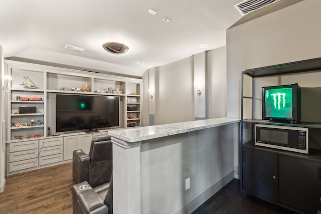 kitchen featuring visible vents, dark wood-style floors, stainless steel microwave, light stone countertops, and white cabinetry