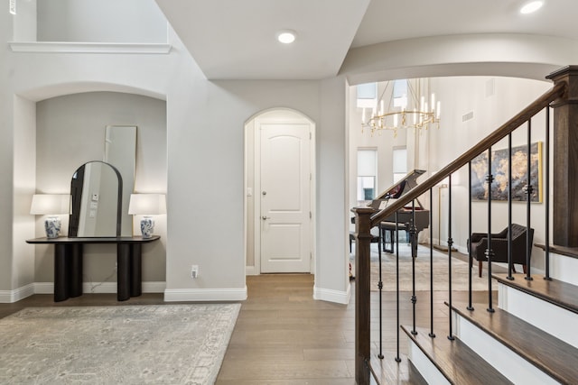 entrance foyer with a notable chandelier, recessed lighting, stairway, wood finished floors, and baseboards