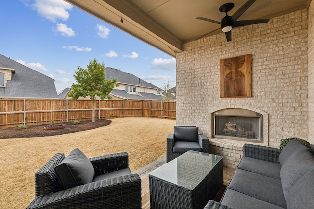 view of patio / terrace with a ceiling fan, a fenced backyard, and an outdoor living space with a fireplace