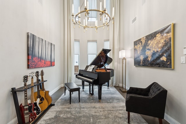 living area with a chandelier, baseboards, visible vents, and a high ceiling