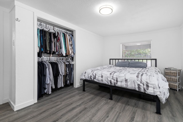 bedroom with a textured ceiling, baseboards, a closet, and wood finished floors