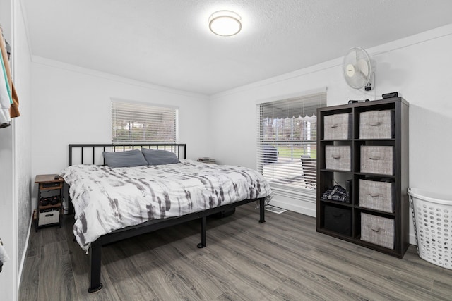 bedroom with a textured ceiling, wood finished floors, and crown molding