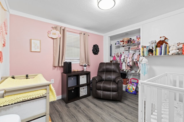 bedroom with a textured ceiling, baseboards, and wood finished floors