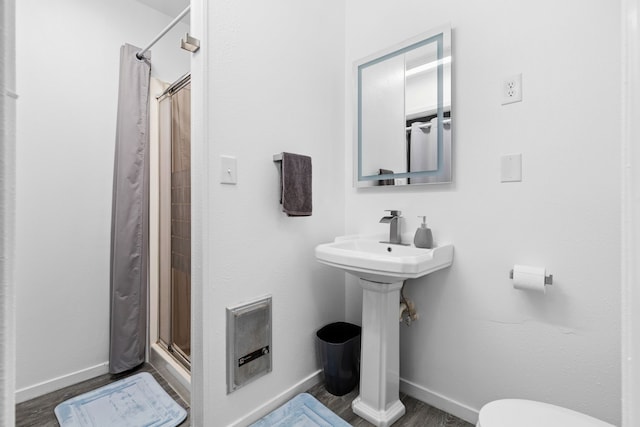 full bathroom with toilet, a stall shower, baseboards, and wood finished floors