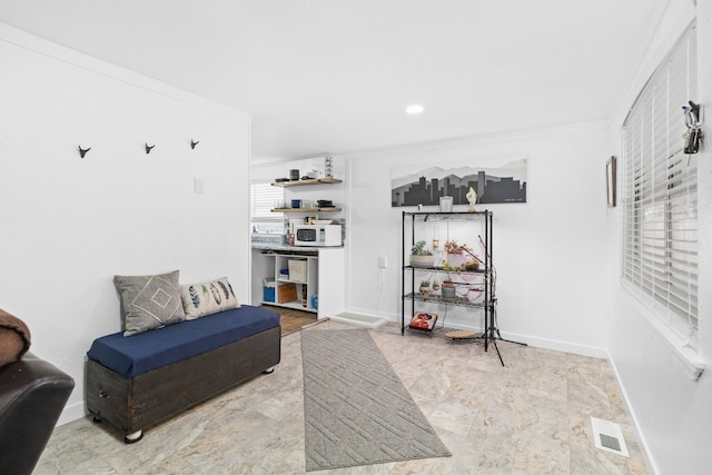 living area with visible vents, crown molding, and baseboards