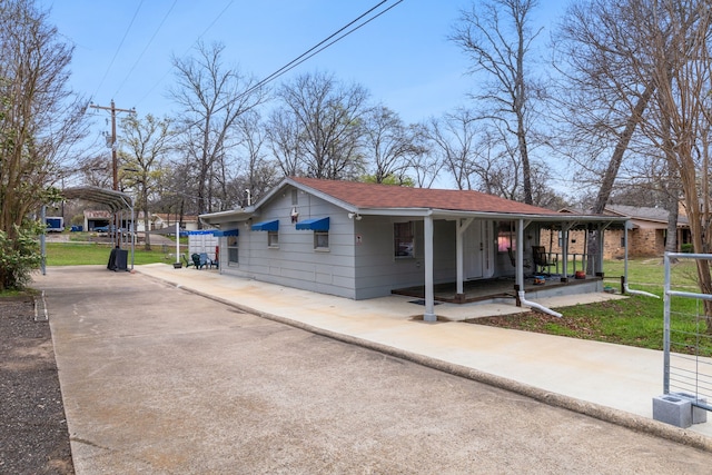 view of property exterior featuring covered porch, driveway, a yard, and roof with shingles