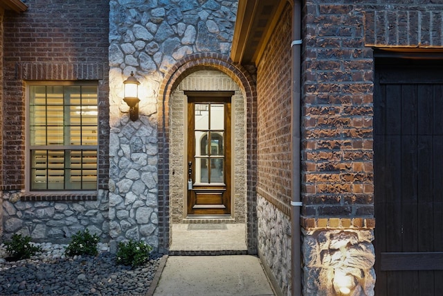 view of exterior entry featuring stone siding and brick siding