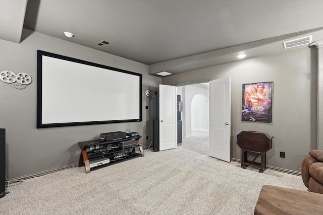 carpeted home theater room featuring baseboards, visible vents, and arched walkways