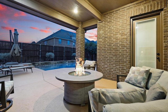 patio terrace at dusk with fence and an outdoor living space with a fire pit