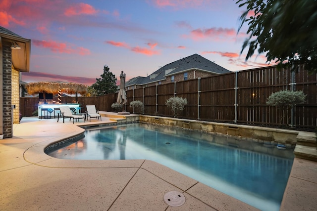 pool at dusk featuring a fenced backyard, a fenced in pool, and a patio