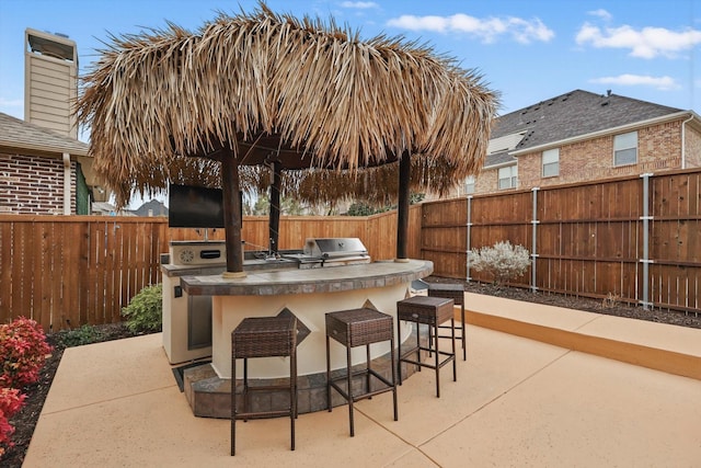 view of patio / terrace with a fenced backyard, a grill, outdoor dry bar, and area for grilling