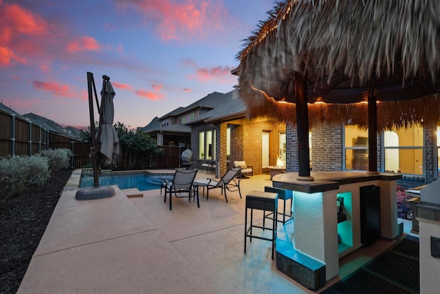 pool at dusk featuring a patio, a fenced backyard, and a fenced in pool