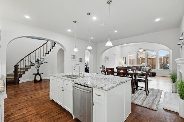 kitchen featuring arched walkways, dark wood finished floors, stainless steel dishwasher, a sink, and ceiling fan