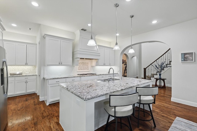 kitchen featuring arched walkways, stainless steel appliances, visible vents, backsplash, and a sink