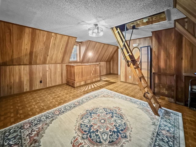 additional living space featuring a textured ceiling and wooden walls