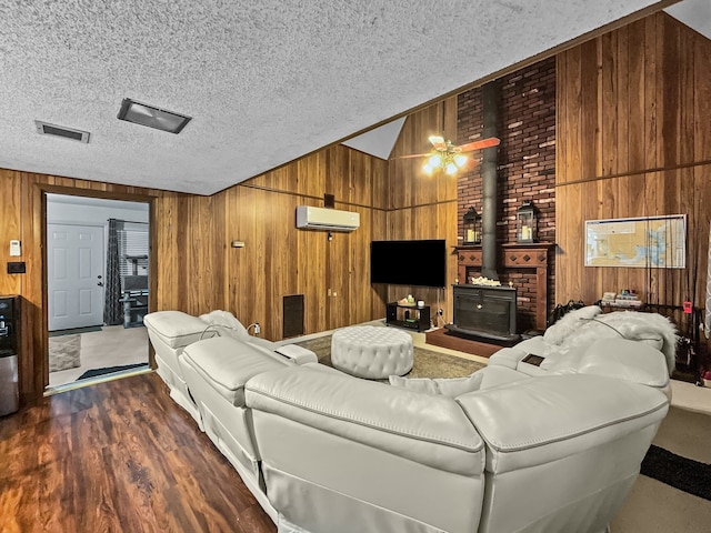 living room featuring lofted ceiling, wood walls, a textured ceiling, and visible vents