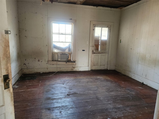 empty room featuring plenty of natural light, cooling unit, and hardwood / wood-style flooring