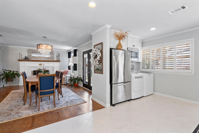 dining space featuring ornamental molding, baseboards, visible vents, and washing machine and clothes dryer