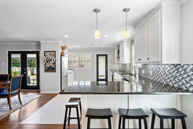 kitchen featuring a sink, white cabinetry, french doors, freestanding refrigerator, and tasteful backsplash