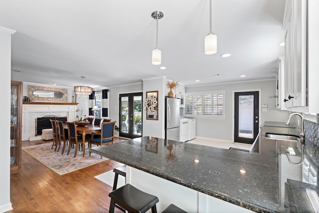 kitchen featuring french doors, ornamental molding, freestanding refrigerator, a sink, and a peninsula