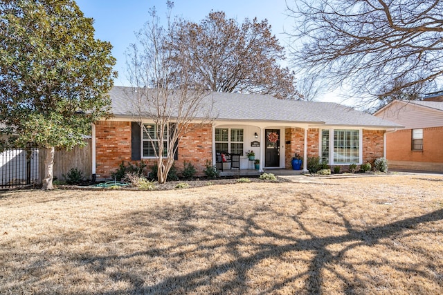 single story home with covered porch, brick siding, roof with shingles, and fence