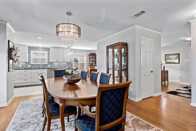 dining area featuring light wood finished floors, visible vents, a chandelier, and ornamental molding