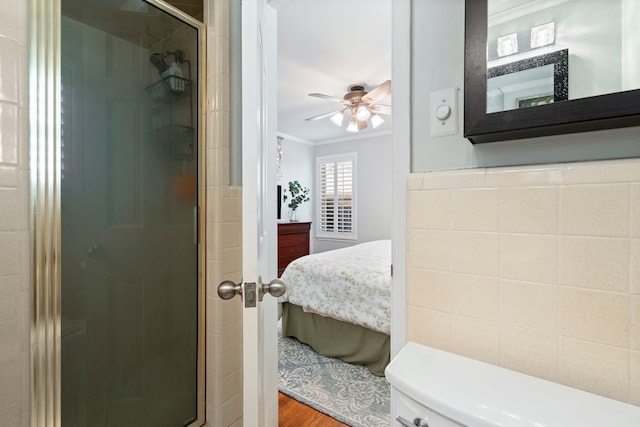 bathroom featuring connected bathroom, wood finished floors, crown molding, a shower stall, and tile walls