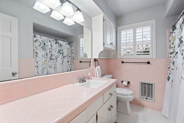 full bath with a wealth of natural light, wainscoting, a textured ceiling, and tile patterned floors