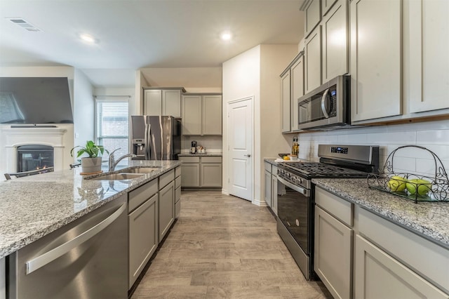 kitchen with appliances with stainless steel finishes, gray cabinets, visible vents, and a sink