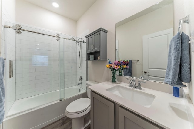 full bath with toilet, bath / shower combo with glass door, wood finished floors, and vanity