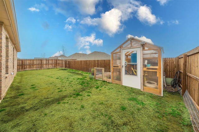 view of yard with an outbuilding, a greenhouse, and a fenced backyard