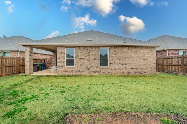 rear view of property with a yard, a patio, brick siding, and a fenced backyard