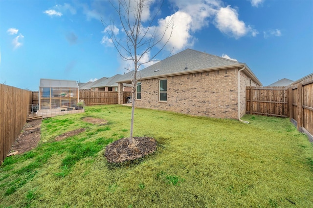 view of yard with an outbuilding, a fenced backyard, and an exterior structure