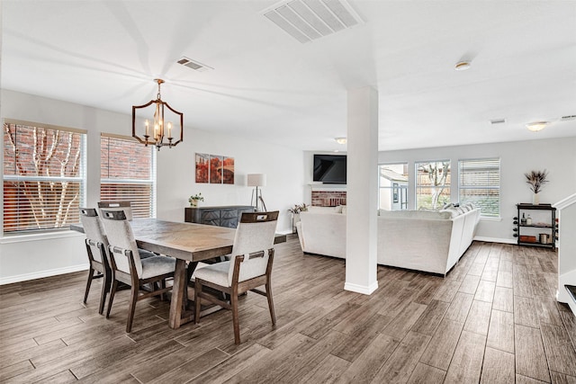 dining area with visible vents, a fireplace, baseboards, and wood finished floors