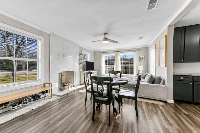 dining area featuring crown molding, visible vents, dark wood-style flooring, and a high end fireplace