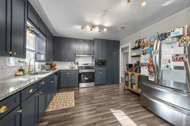 kitchen with visible vents, decorative backsplash, dark wood-style floors, appliances with stainless steel finishes, and a sink