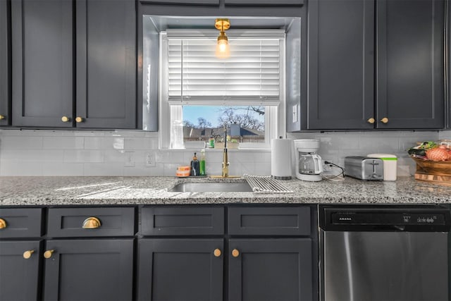 kitchen featuring tasteful backsplash, dishwasher, light stone counters, gray cabinetry, and a sink