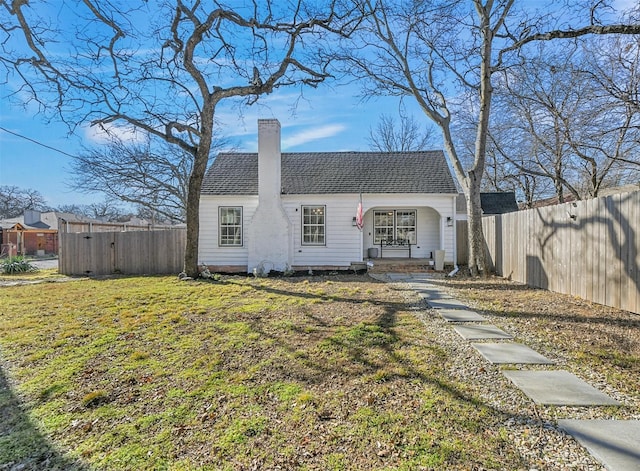 view of front of home with roof with shingles, a chimney, a front yard, and fence