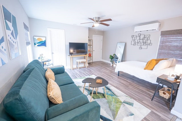 living room featuring a ceiling fan, baseboards, wood finished floors, and a wall mounted AC