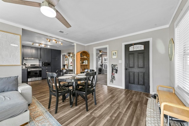 dining room with dark wood-style flooring, visible vents, baseboards, a ceiling fan, and ornamental molding