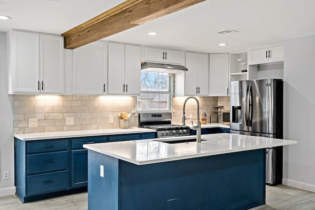 kitchen featuring appliances with stainless steel finishes, blue cabinets, light countertops, light wood-type flooring, and under cabinet range hood