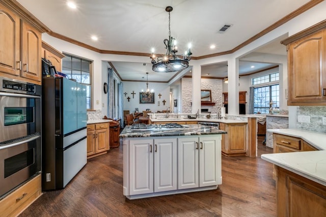 kitchen with dark wood finished floors, decorative backsplash, an inviting chandelier, and stainless steel appliances